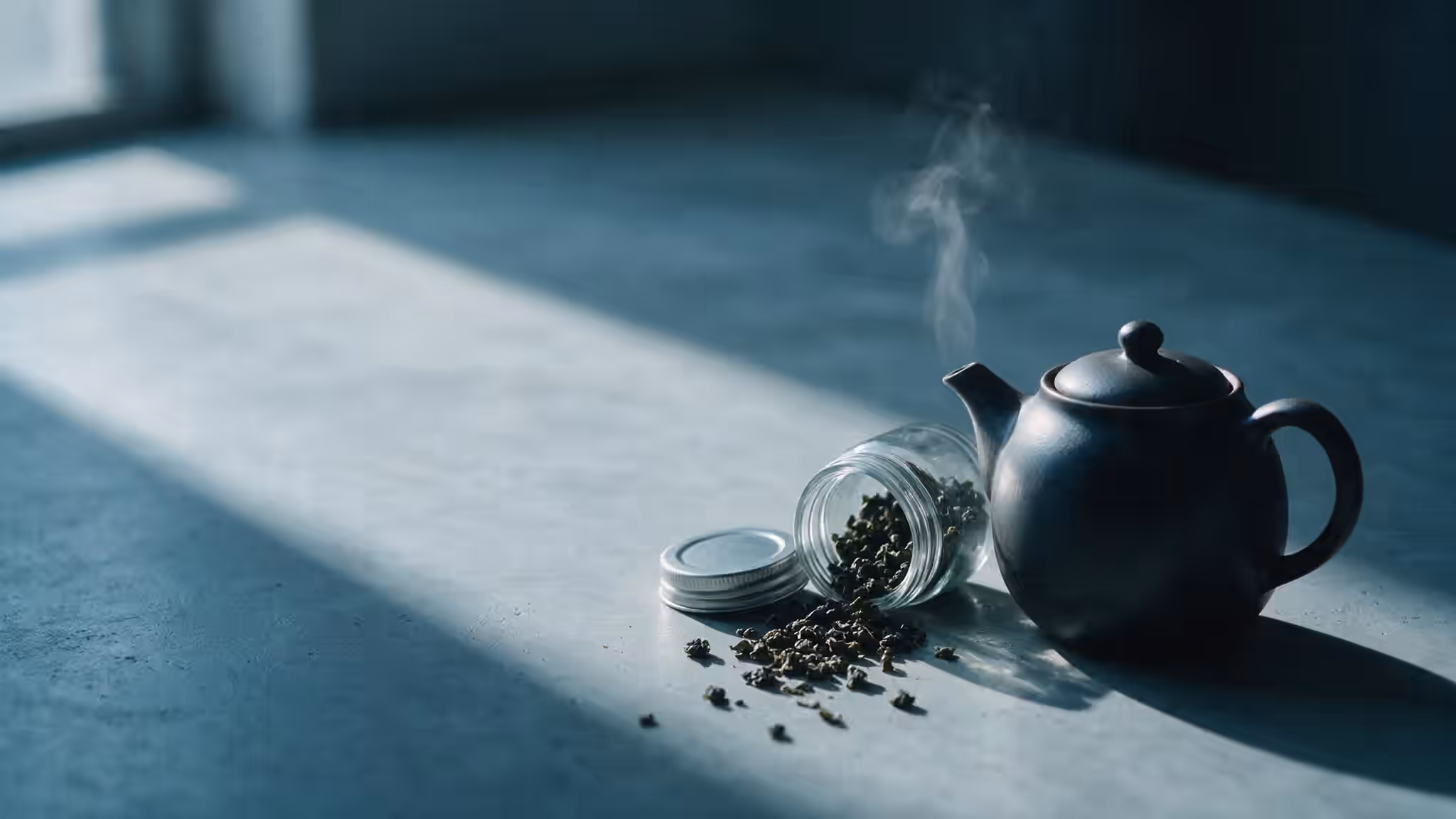 深色陶壺與傾倒的烏龍茶葉罐,冷調光線下的茶桌